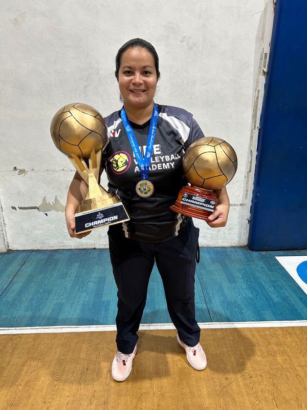 An HDE coach holding two champion trophies