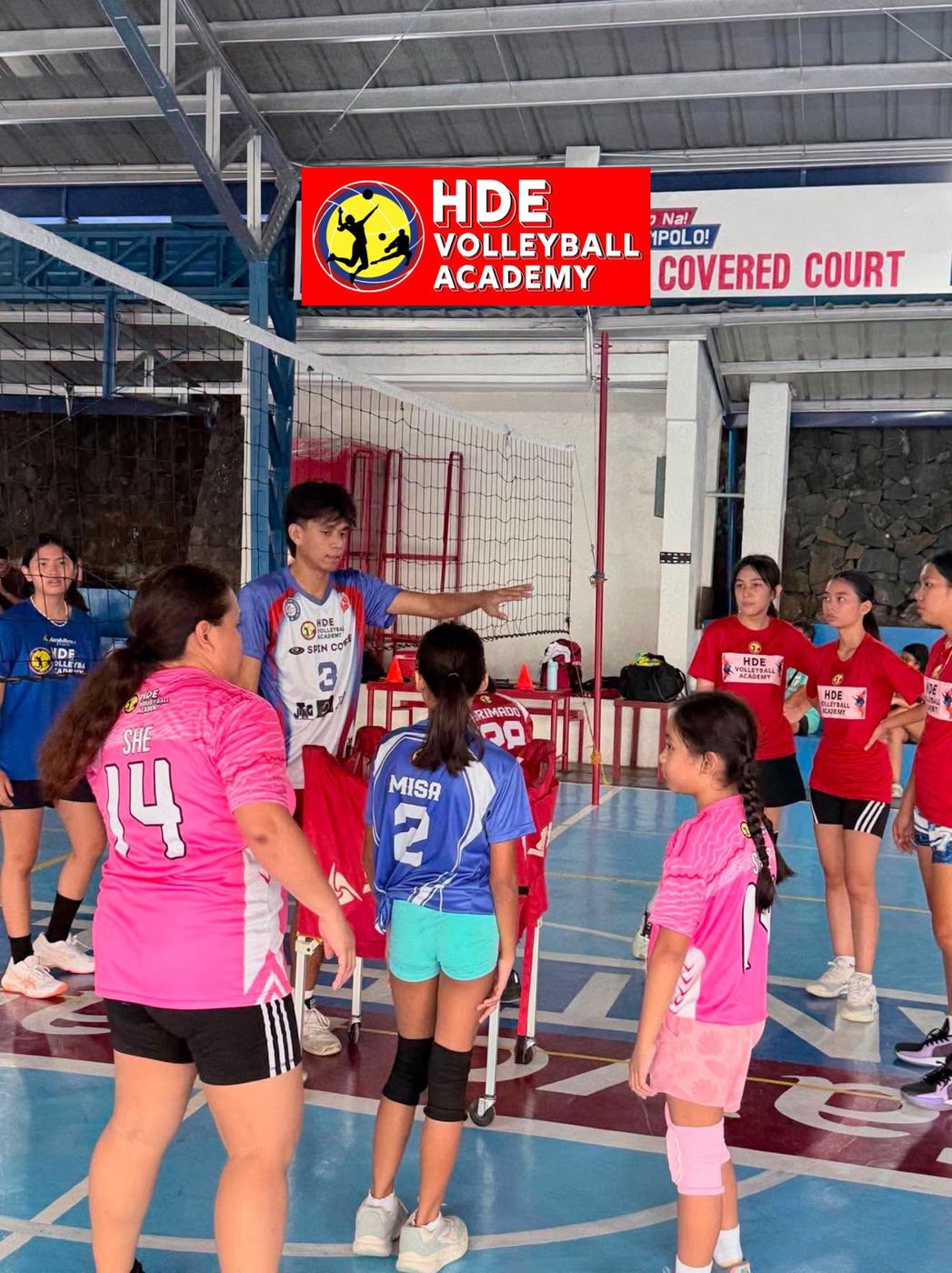 Young HDE campers in pink and blue at a covered court under the HDE banner