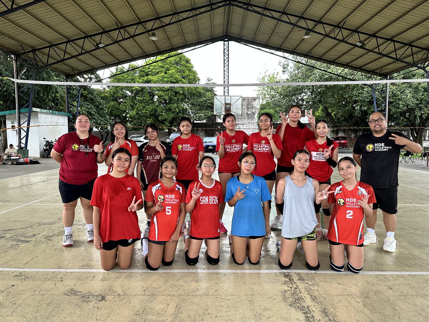Weekend campers in red and blue kneeling under an open covered court